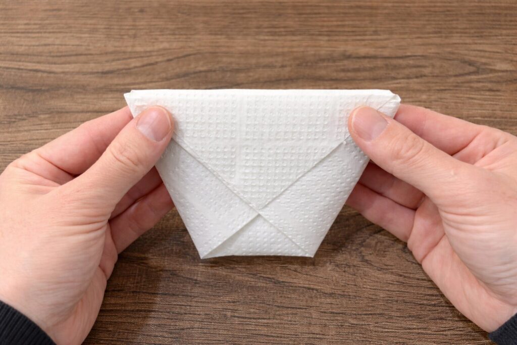 위쪽에 남은 삼각형 부분을 앞으로 접고, 뒤쪽도 같은 방식으로 접어 고정한다.